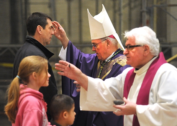 Flanked by Rev. Msgr. David S. Slubecky, Vicar General, Bishop Richard J. Malone distributes ashes at the 12:05 p.m. Mass at St. Joseph Cathedral. (Dan Cappellazzo/Staff Photographer )